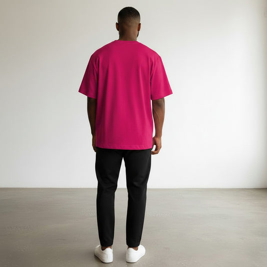 Back view of a man wearing a BREAKPOINT Sportswear hot pink oversized drop-shoulder tee with black joggers and white sneakers