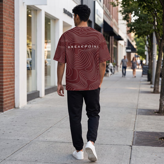 BREAKPOINT Sportswear maroon drop-shoulder tee with white topographic print worn by a man walking on a city sidewalk.