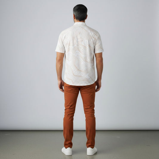 Back view of a man wearing a BREAKPOINT Sportswear white performance polo with topographic lines and burnt orange pants.