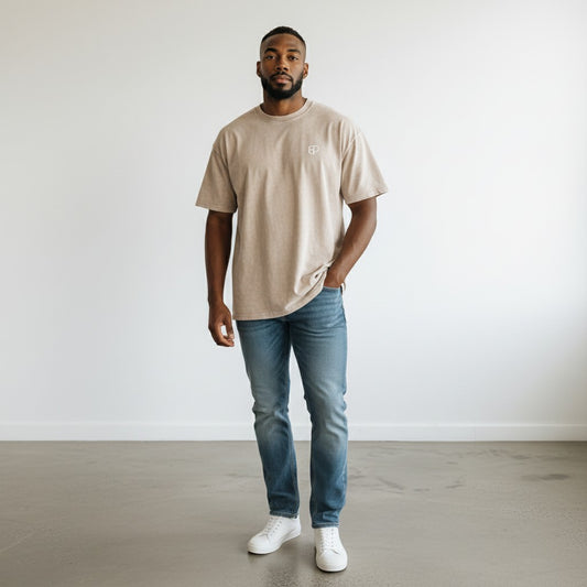 Model wearing a BREAKPOINT Sportswear apricot oversized snow-wash cotton t-shirt with blue jeans and white sneakers.