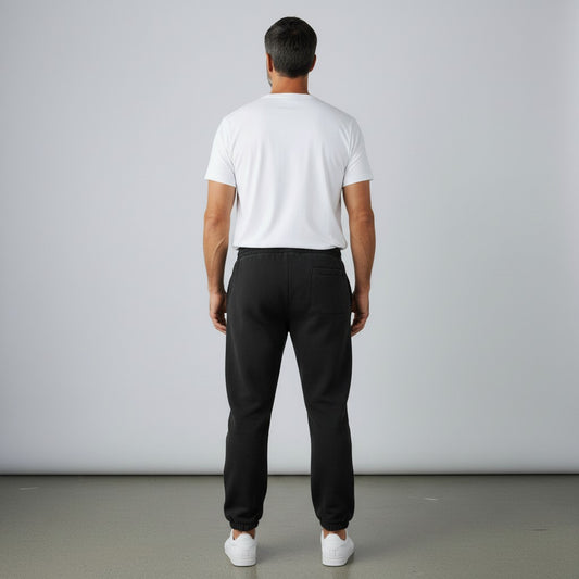 Back view of a man wearing black BREAKPOINT Sportswear fleece sweatpants with cuffed ankles and a white t-shirt.