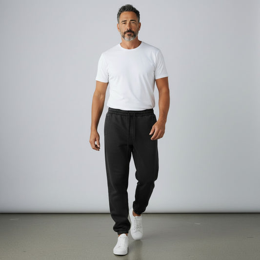 Man wearing BREAKPOINT Sportswear black fleece sweatpants with a white t-shirt and sneakers in a studio setting