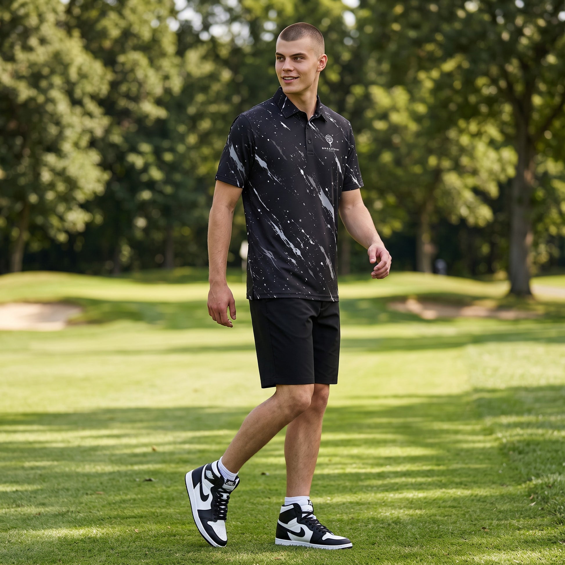 BREAKPOINT Sportswear men's black heavyweight polyester polo with white splatter print, worn by a golfer on a course.