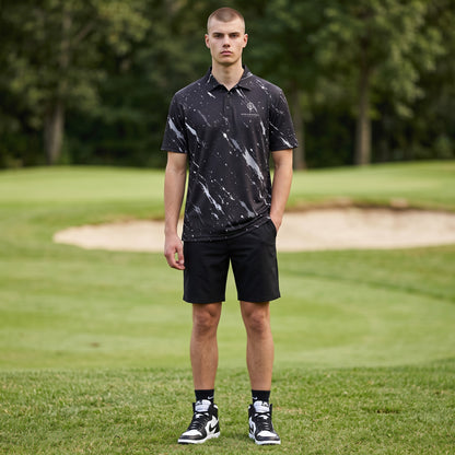 BREAKPOINT Sportswear black polo with white splatter print, worn by a man on a golf course.