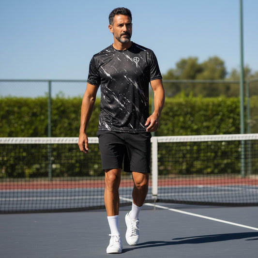 A male athlete wearing a BREAKPOINT Sportswear black splatter print performance tennis tee on a court.