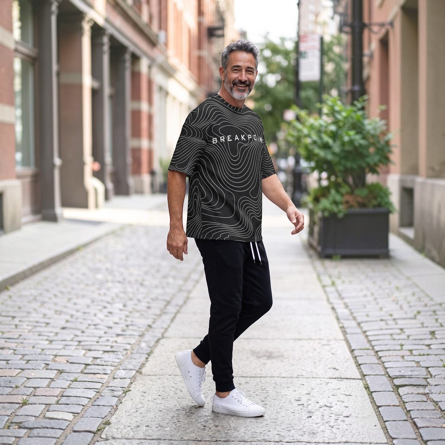 BREAKPOINT Sportswear black and white drop-shoulder tee with topographic print worn by a man on a city street.