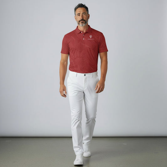 BREAKPOINT Sportswear crimson performance golf polo with subtle topographic pattern, worn with white trousers by a man.