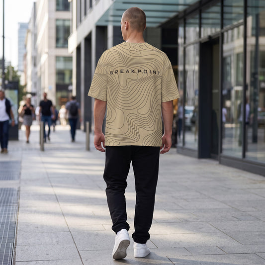 BREAKPOINT Sportswear gold and black drop-shoulder tee with topographic print worn by a man walking on a city street.