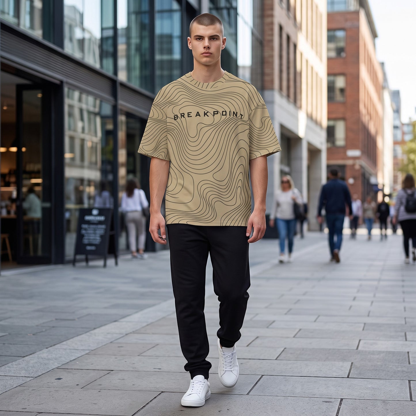 BREAKPOINT Sportswear gold and black drop-shoulder tee with topographic print worn by a man on a city street.