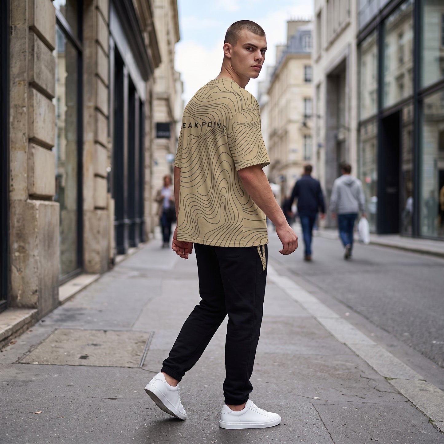 BREAKPOINT Sportswear gold and black drop-shoulder tee with topographic line print worn by a man on a city street.