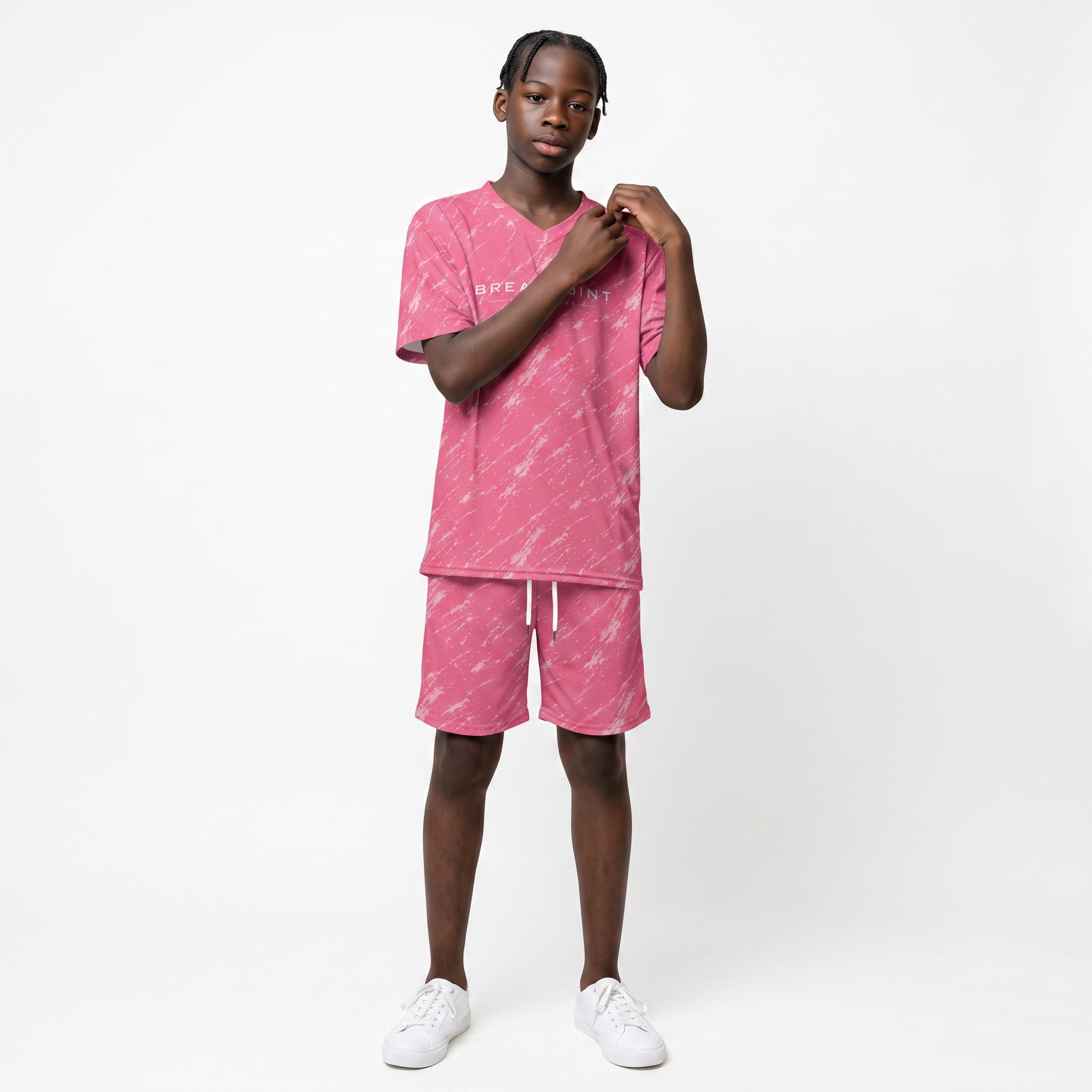 A young boy wearing a pink BREAKPOINT Sportswear V-neck tee and matching drawstring shorts with an all-over print.