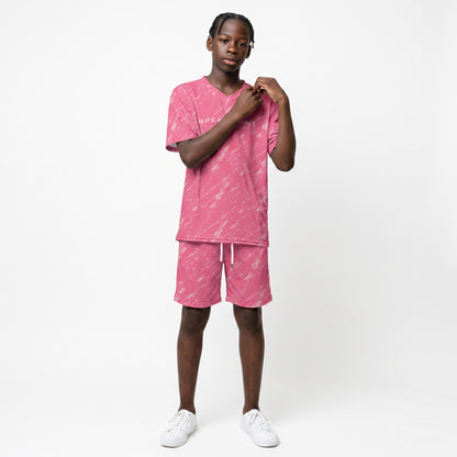 A young boy wearing a pink BREAKPOINT Sportswear V-neck tee and matching drawstring shorts with an all-over print.
