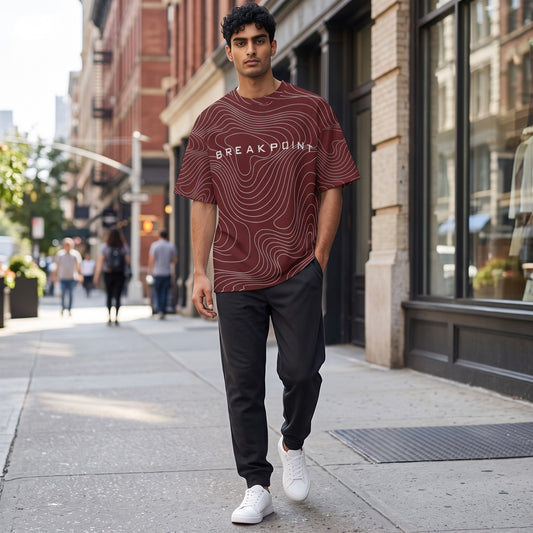BREAKPOINT Sportswear maroon drop-shoulder tee with white topographic print worn by a man on a city sidewalk.