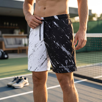 BREAKPOINT Sportswear men's athletic mesh shorts with a black and white paint splatter design on a tennis court.