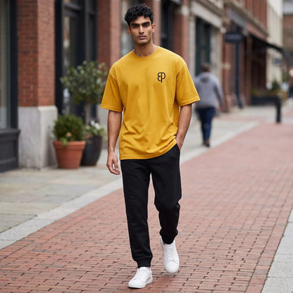 BREAKPOINT Sportswear unisex mustard yellow drop-shoulder t-shirt with logo, worn by a man on a city street.