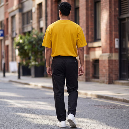 BREAKPOINT Sportswear unisex drop-shoulder t-shirt in mustard yellow worn by a man walking on a city street