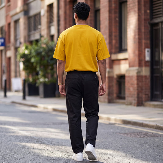 BREAKPOINT Sportswear unisex drop-shoulder t-shirt in mustard yellow worn by a man walking on a city street