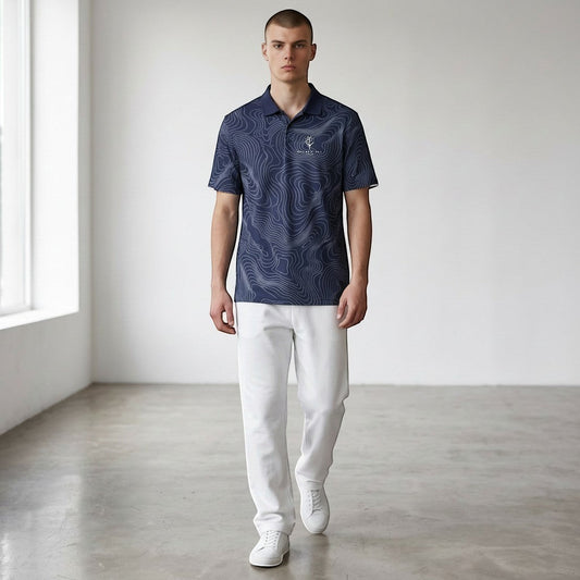 Model wearing a BREAKPOINT Sportswear navy performance polo with a white topographic print and white trousers.