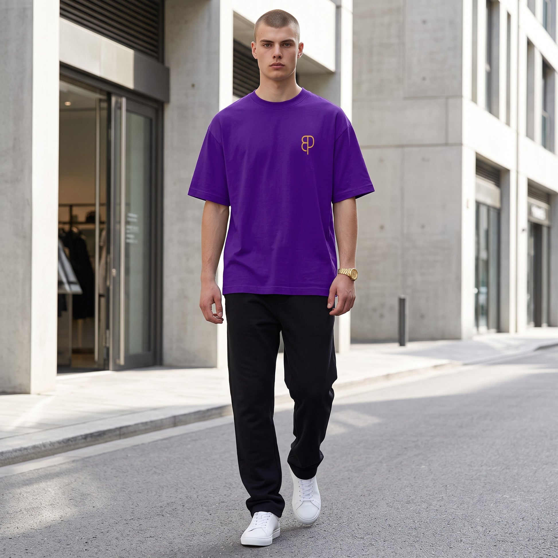 BREAKPOINT Sportswear unisex purple drop-shoulder t-shirt with gold logo, worn by a man on a city street.