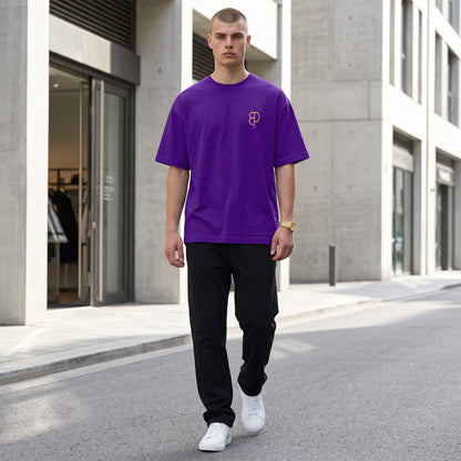 BREAKPOINT Sportswear unisex purple drop-shoulder t-shirt with gold logo, worn by a man on a city street.