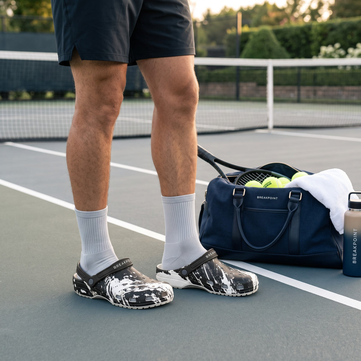 BREAKPOINT Sportswear BREAKPOINT Clog in black and white Splatter Shock print worn with grey socks on a tennis court
