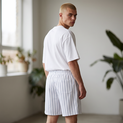 BREAKPOINT Sportswear unisex court shorts in white with blue pinstripes, worn by a model in a bright studio.