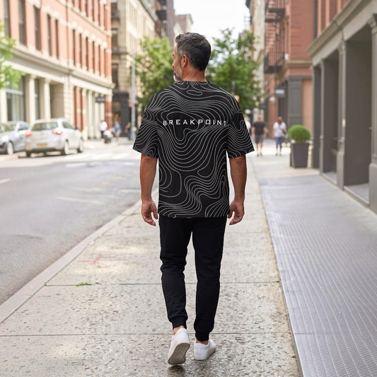 BREAKPOINT Sportswear black and white topographic print drop-shoulder tee worn by a man walking on a city street.