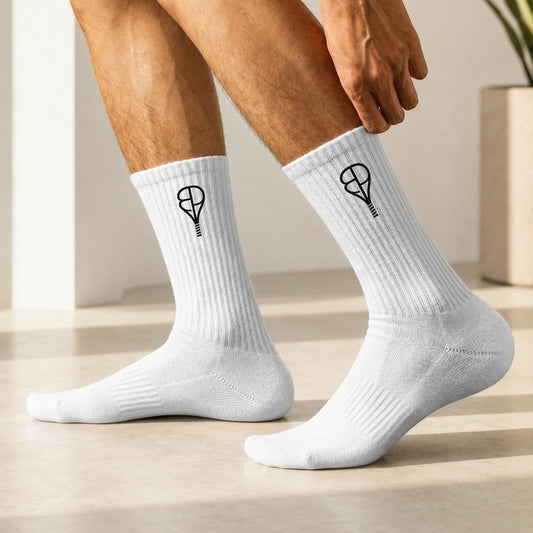 BREAKPOINT Sportswear white cotton crew socks with black embroidered tennis racket logo on a person's feet