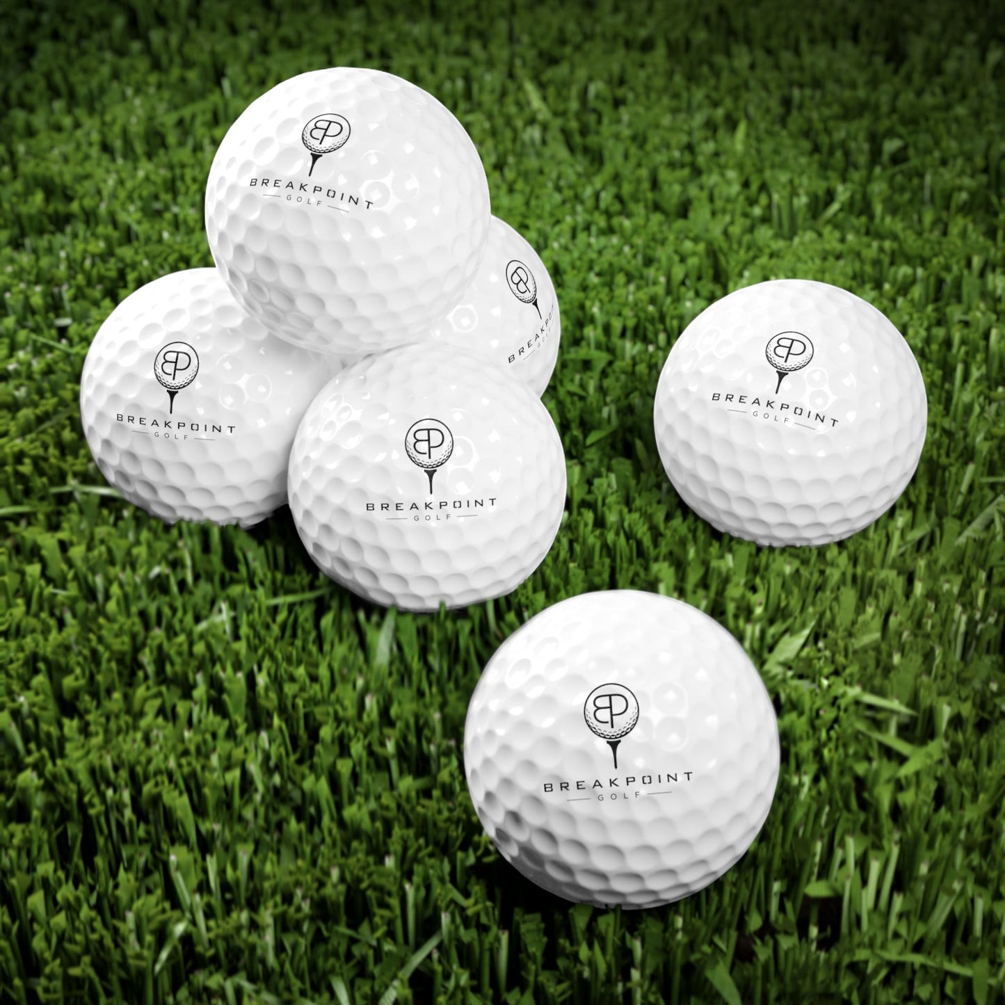 BREAKPOINT Sportswear golf ball six-pack with durable white Surlyn covers and crisp black branding on green grass