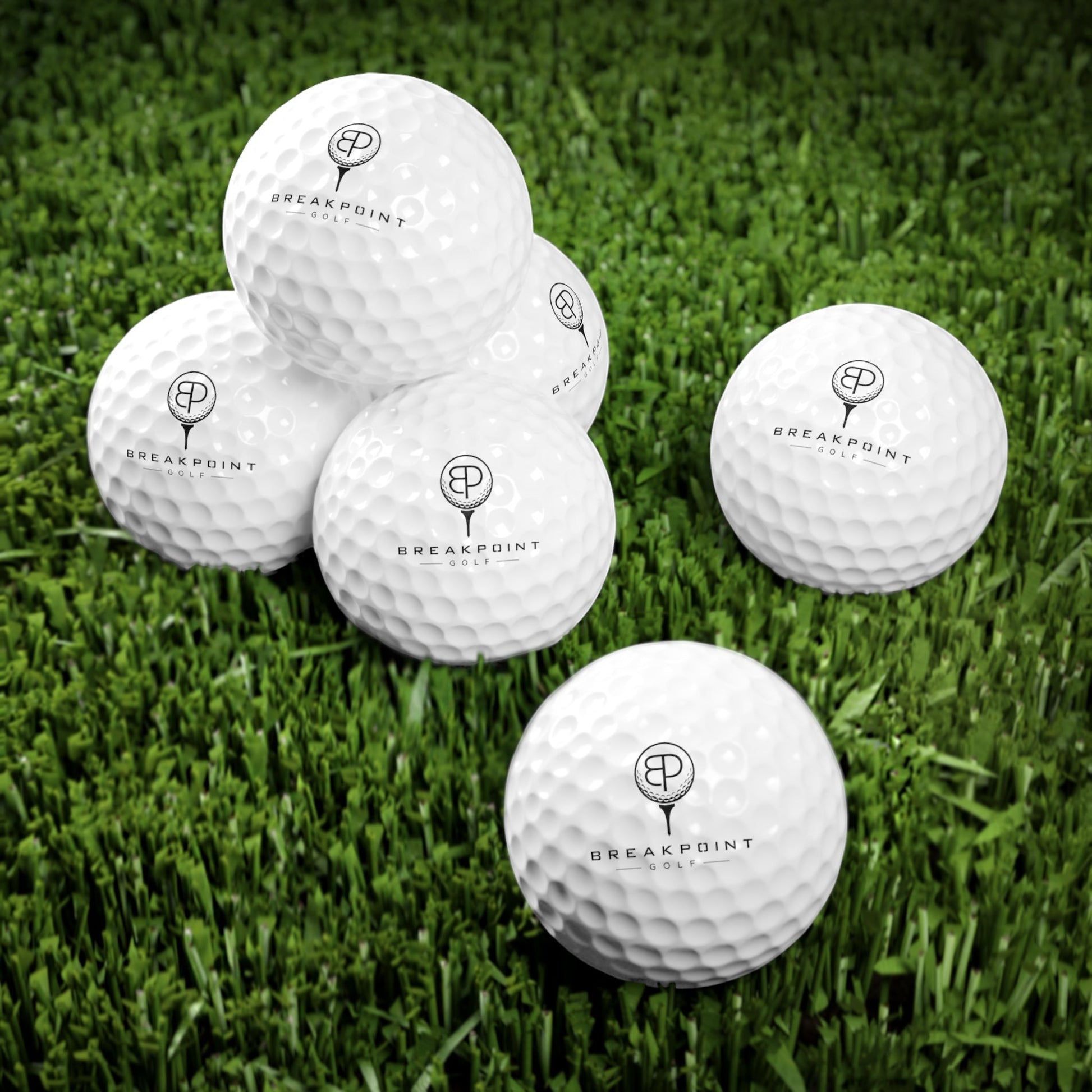 BREAKPOINT Sportswear golf ball six-pack with durable white Surlyn covers and crisp black branding on green grass