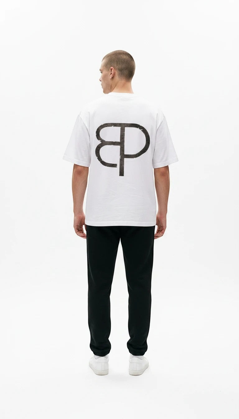 BREAKPOINT Sportswear white cotton Identity Tee with a large black logo on the back, worn by a man in black joggers.