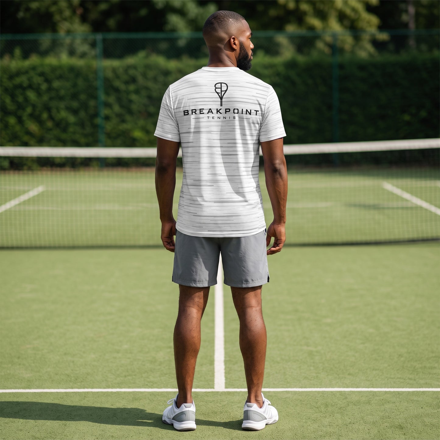 BREAKPOINT Sportswear white performance tee with static print worn by a man on a tennis court from the back view.
