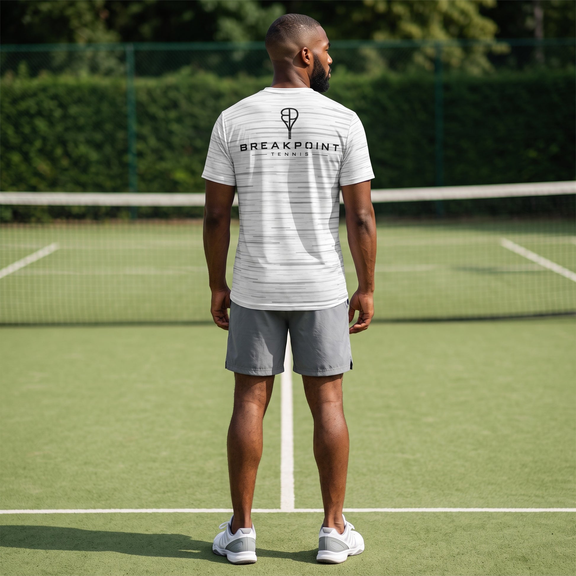 BREAKPOINT Sportswear white performance tee with static print worn by a man on a tennis court from the back view.