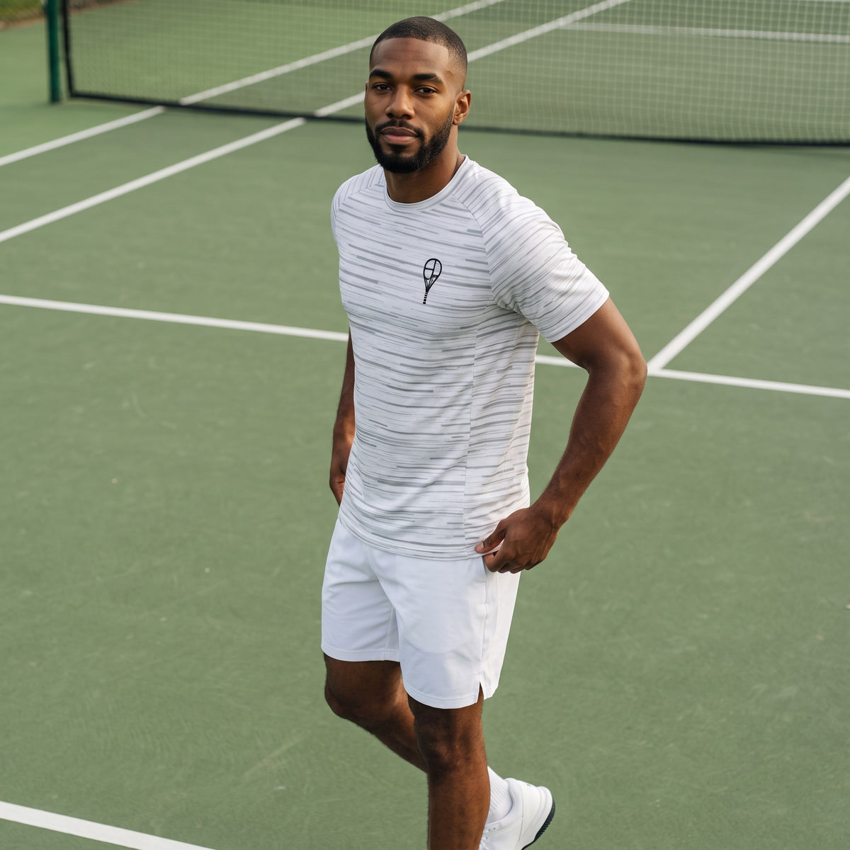 BREAKPOINT Sportswear white performance tee with grey static print worn by a man on a tennis court.