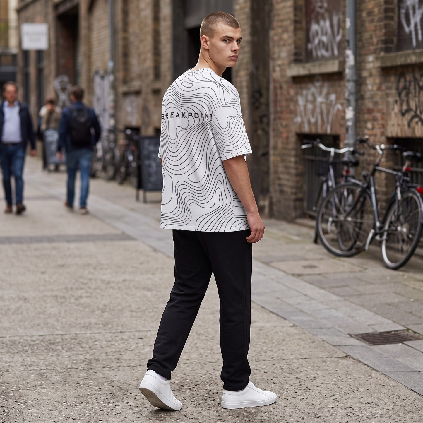 BREAKPOINT Sportswear white drop-shoulder tee with black topographic line print worn by a man in an urban setting.