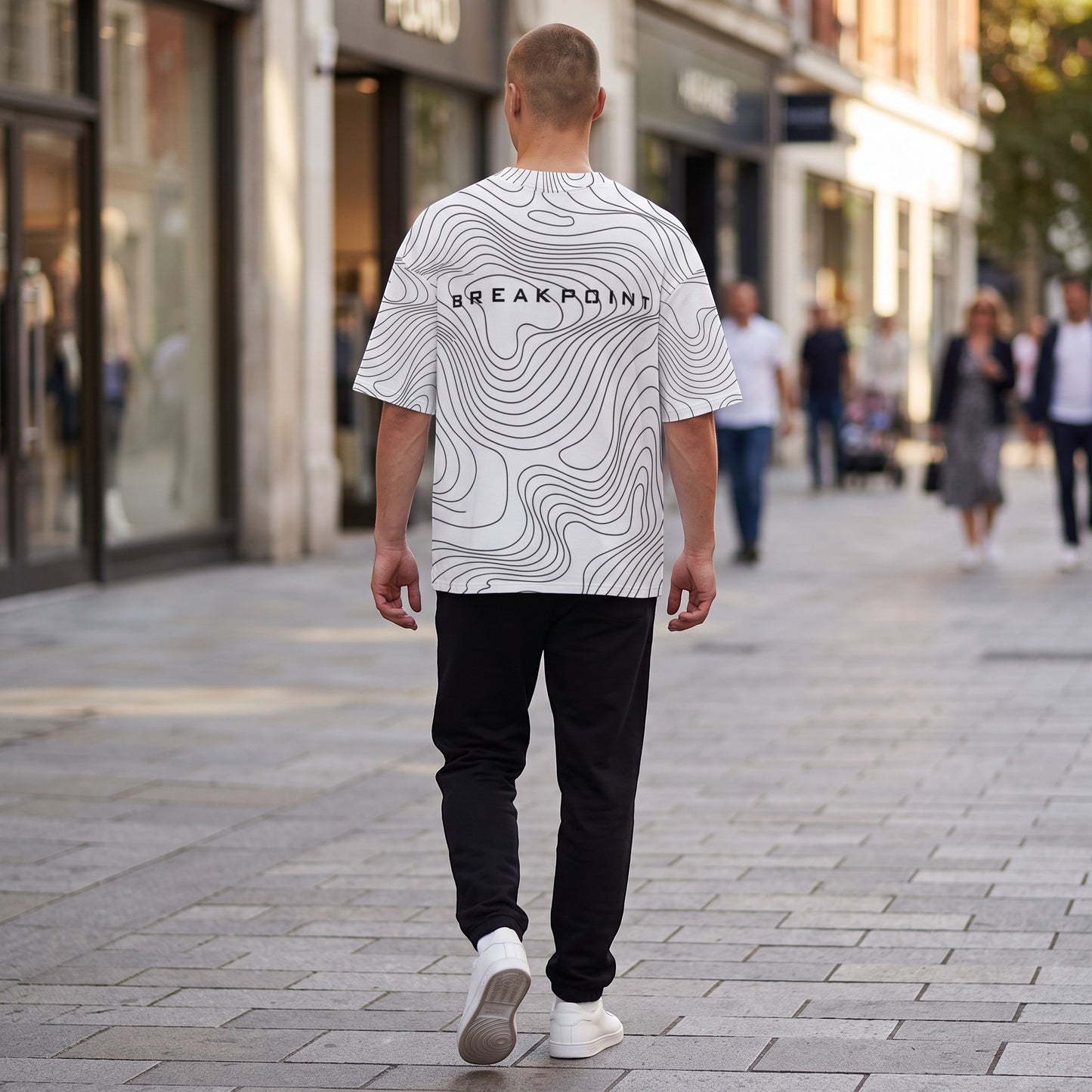 BREAKPOINT Sportswear white drop-shoulder tee with black topographic line print worn by a man on a city street.