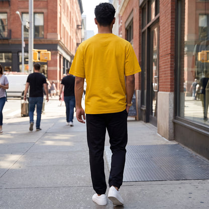 BREAKPOINT Sportswear unisex yellow drop-shoulder t-shirt worn by a man walking on a city street